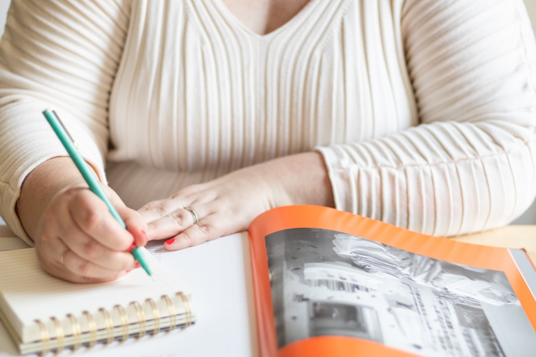 a woman sitting at a desk with a notebook and pen