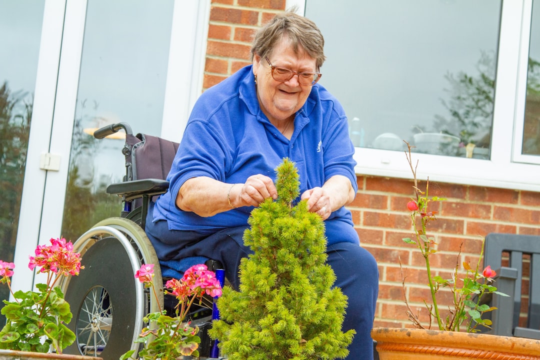 Elderly woman in wheelchair tending to small plant