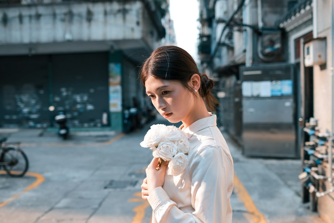 Young woman holding white flowers in an urban alley