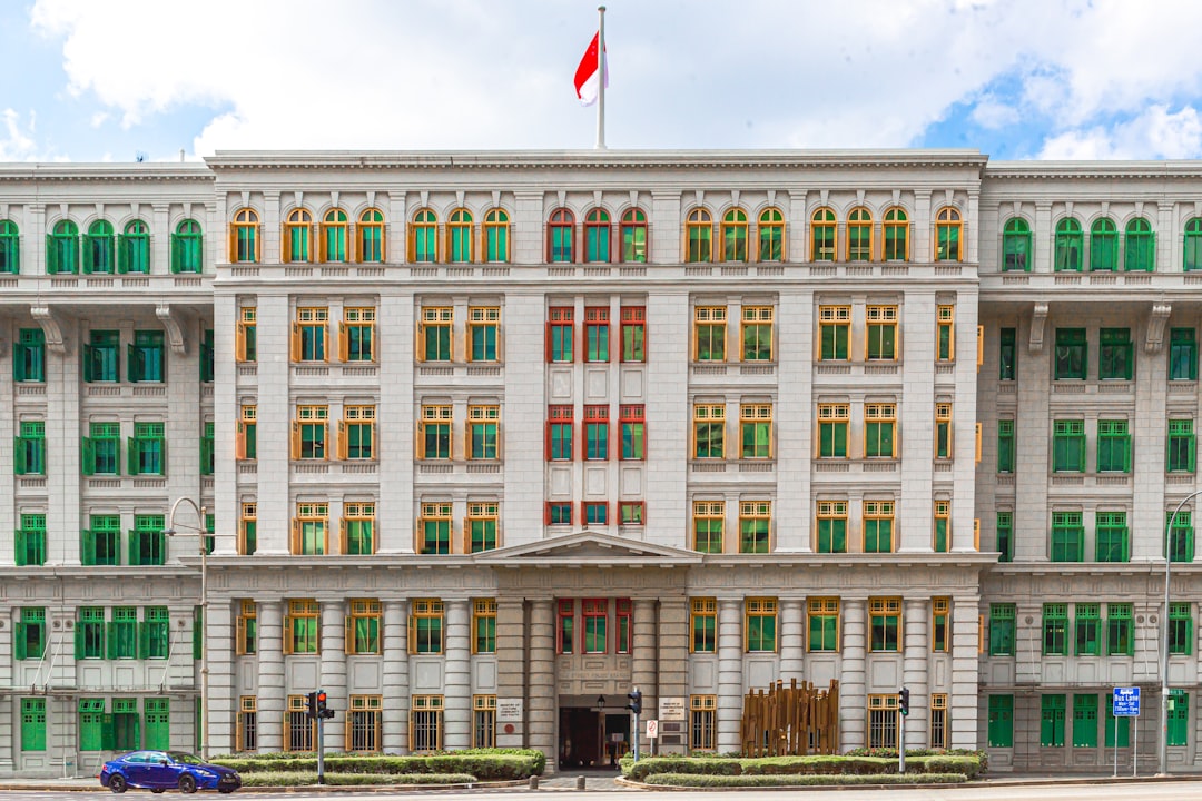 a large white building with green shutters and a flag on top of it
