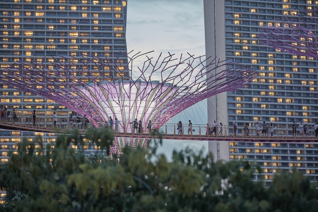 a group of people walking across a bridge in front of tall buildings
