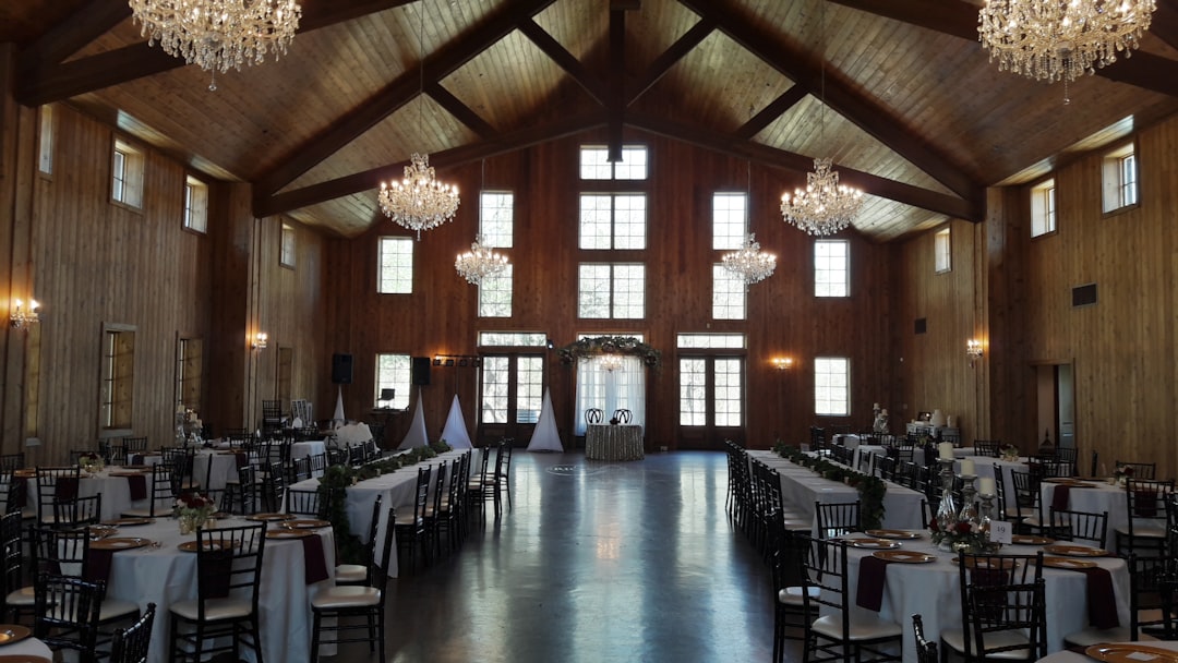Elegant wedding reception hall with wooden beams and crystal chandeliers.