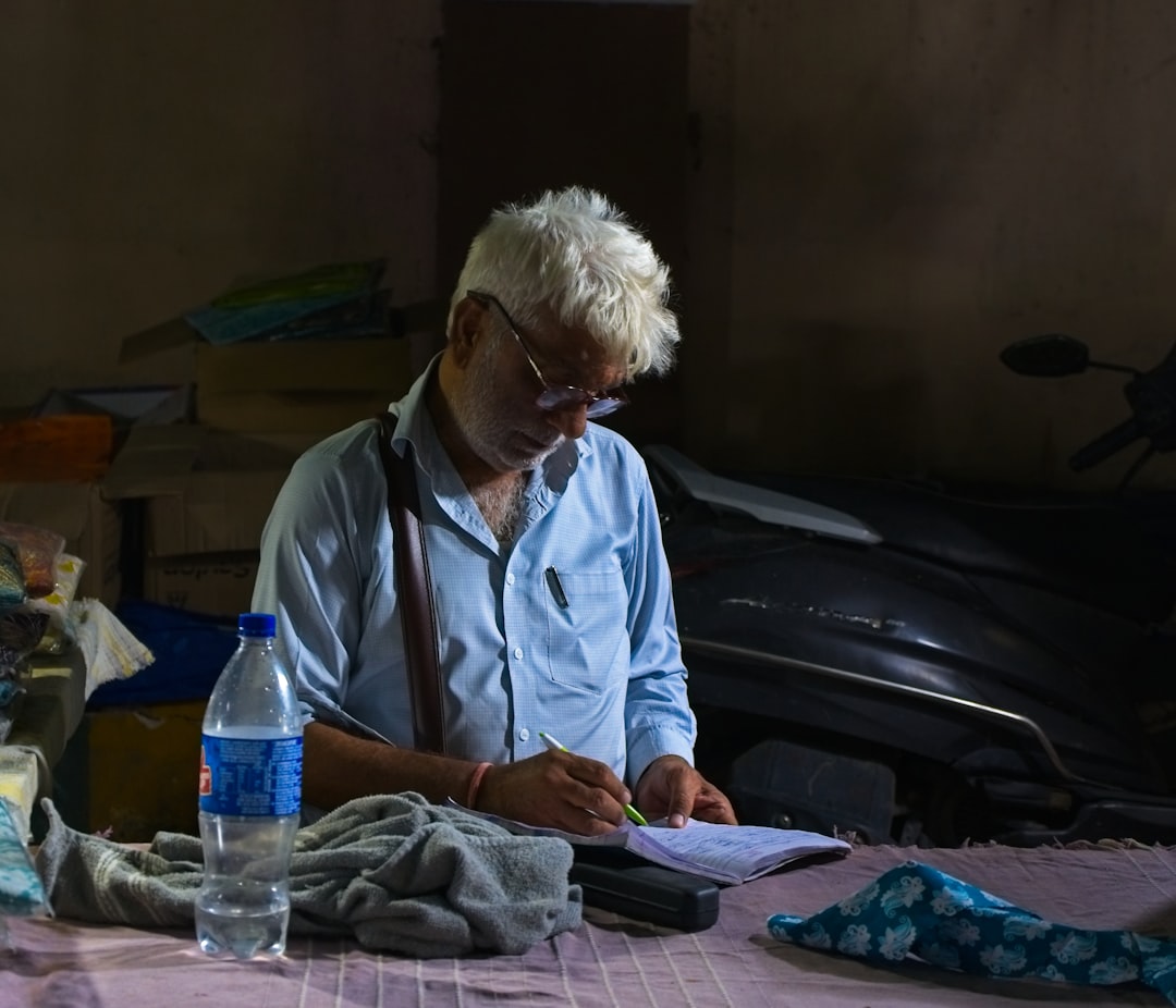 An elderly man is writing at a desk.