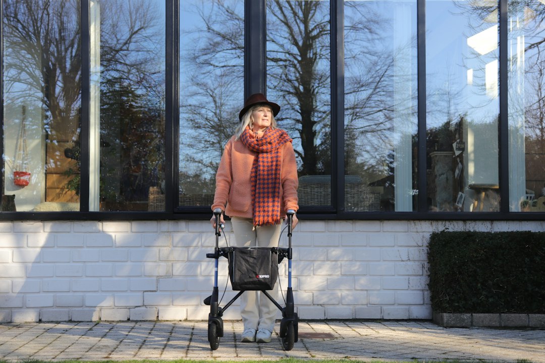 Elderly woman with walker in front of large windows