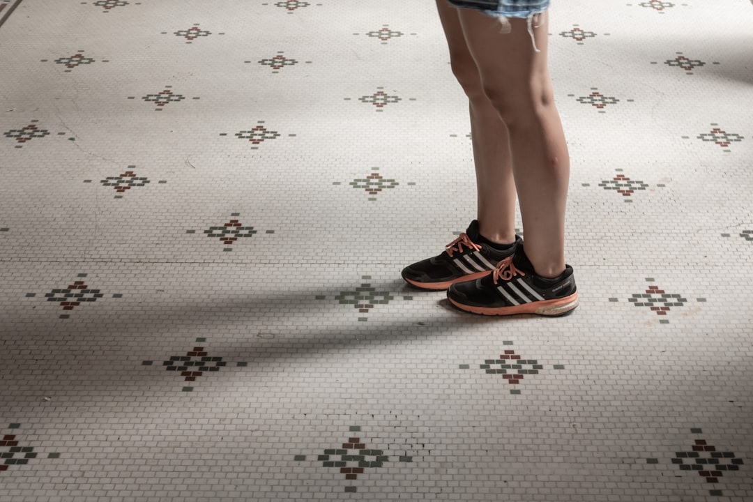 person wearing black-and-orange adidas sneakers