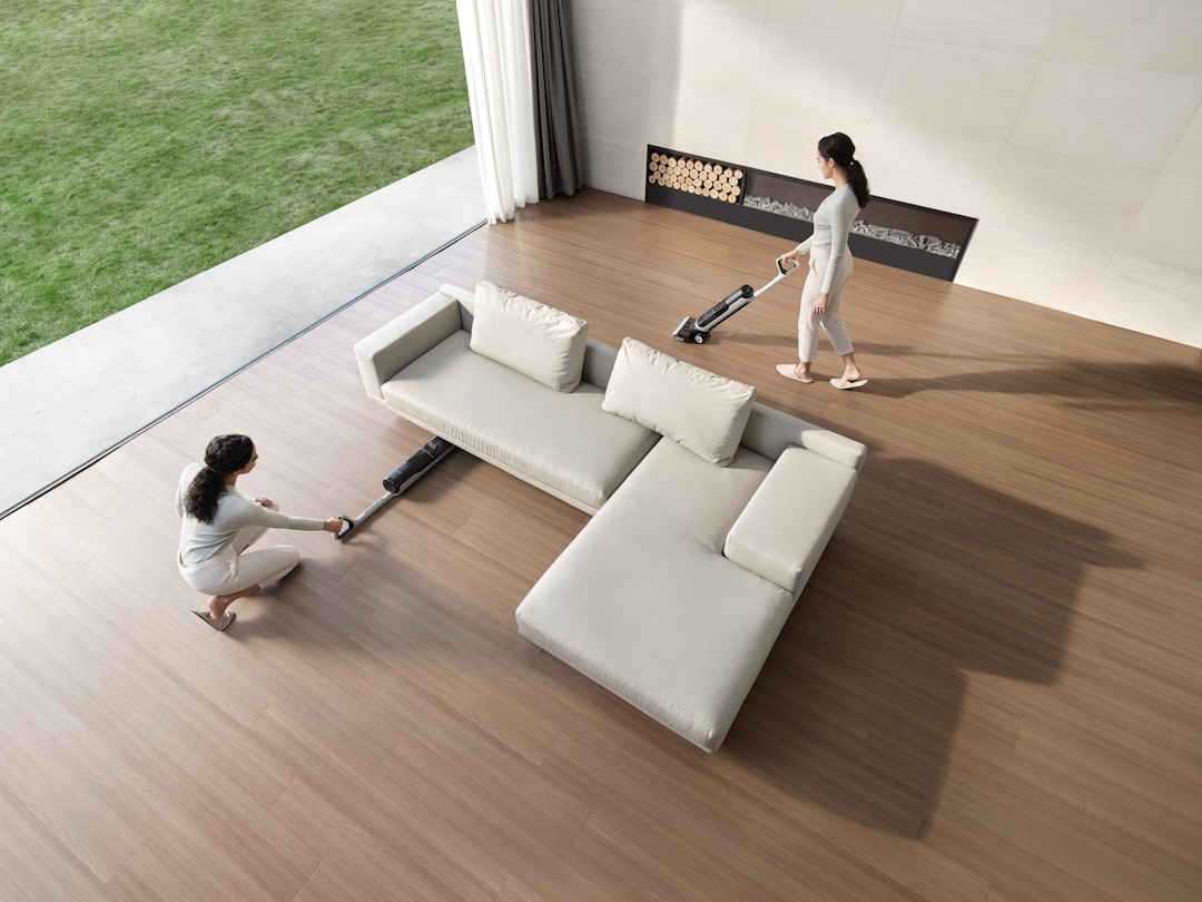 Two women cleaning a modern living room with vacuum cleaners.