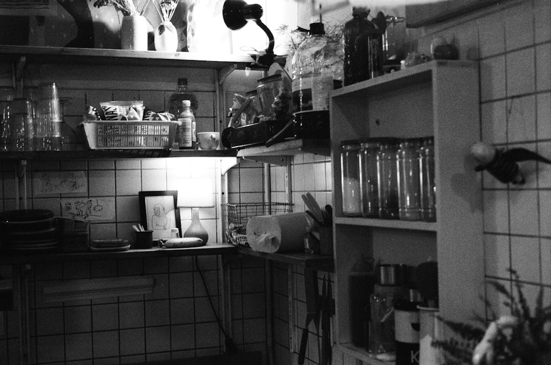 A cluttered kitchen shelf with jars and utensils