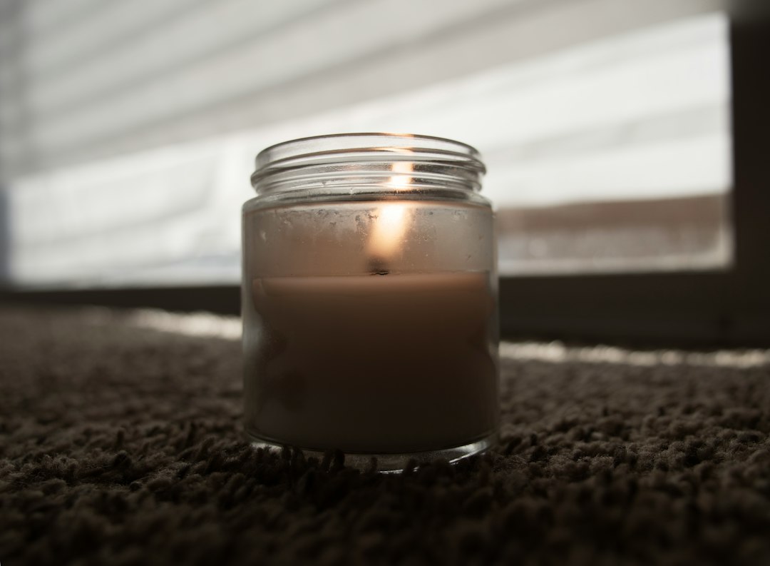clear glass candle holder on brown textile