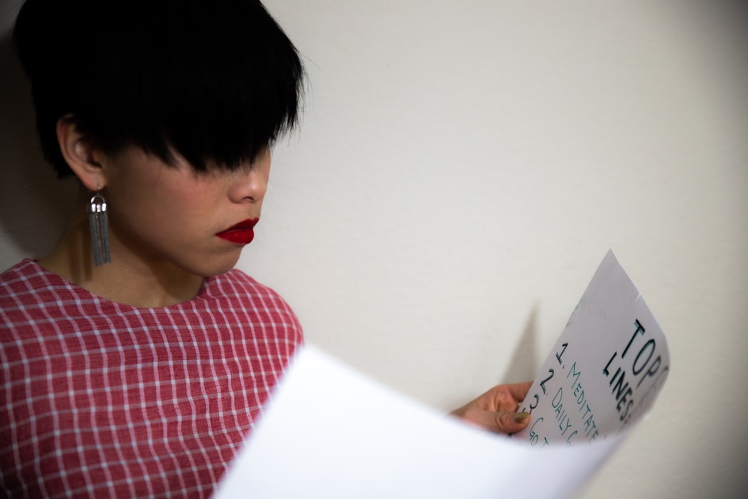 boy in red and blue plaid shirt holding white printer paper
