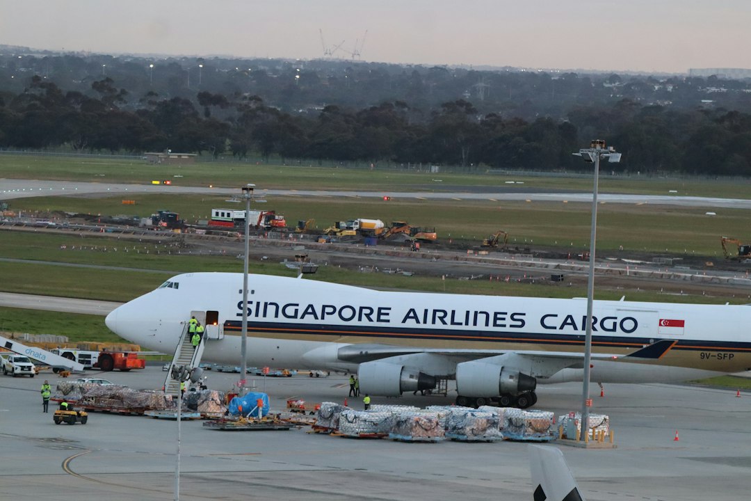 A Singapore Airlines Cargo plane parked on an airport tarmac with ground crew