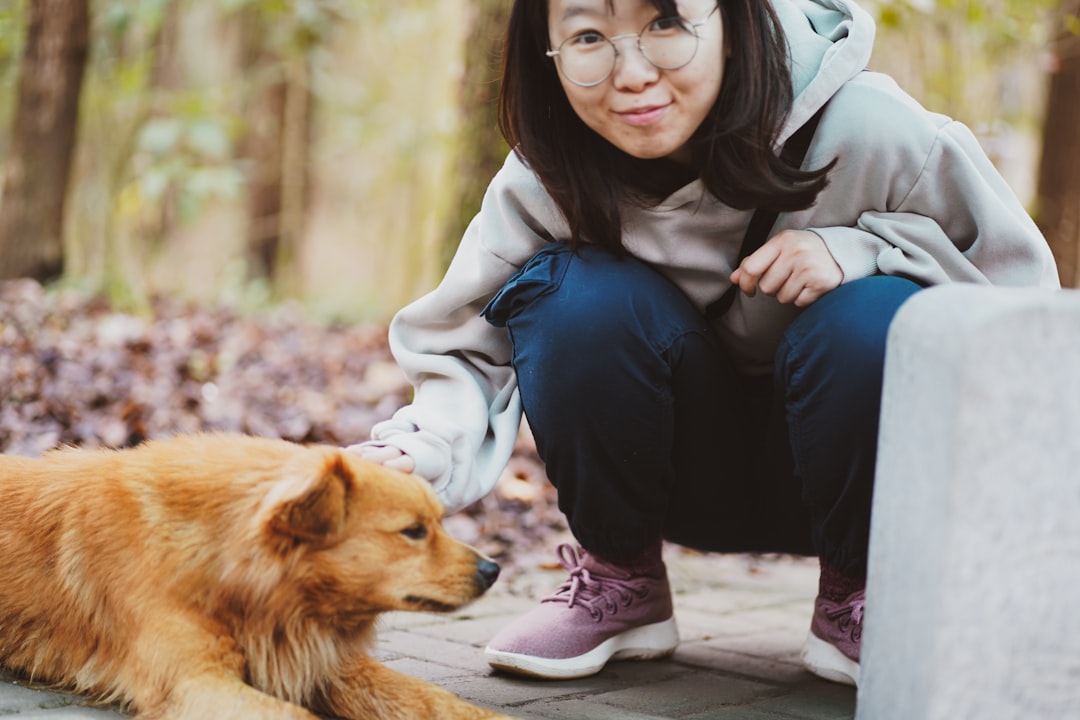woman in gray jacket hugging brown dog
