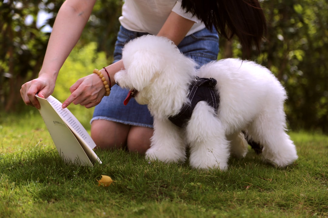 woman holding and pointing on book page beside dog