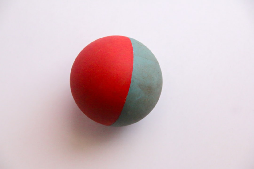 A red and green ball sitting on top of a white table