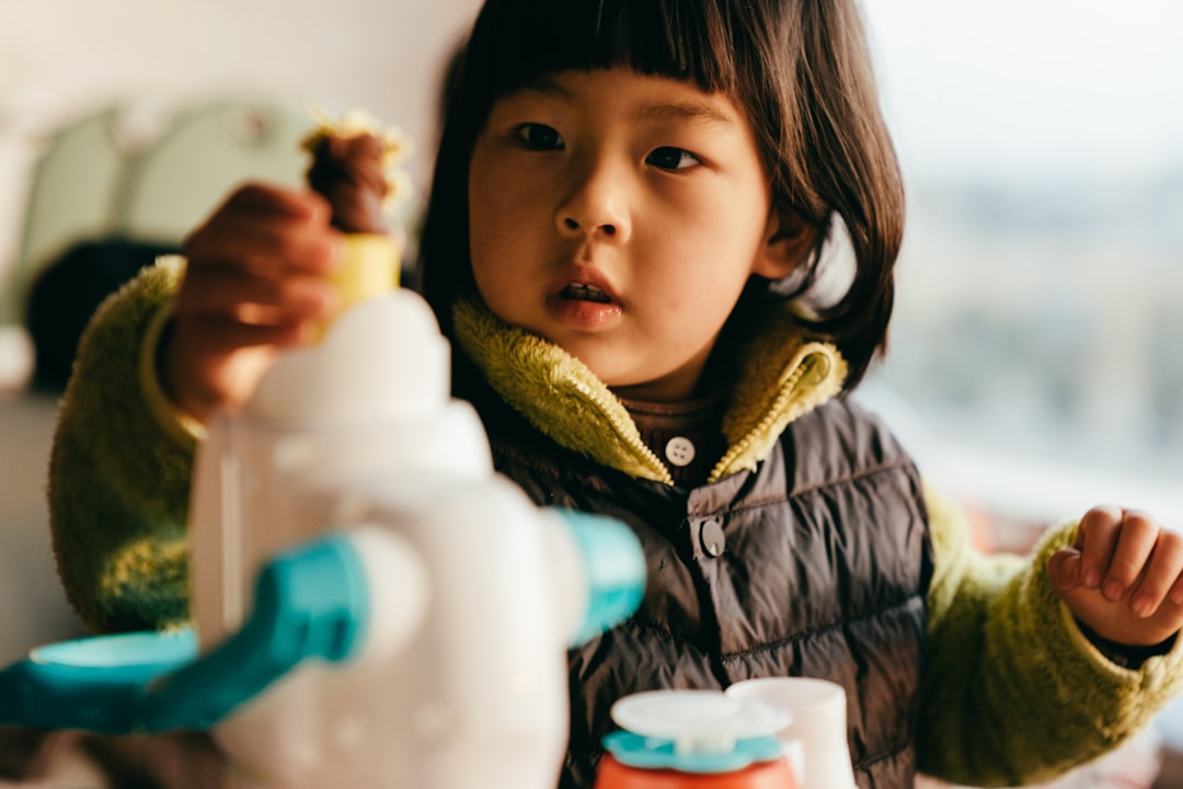 girl in blue and white jacket holding white plastic bottle