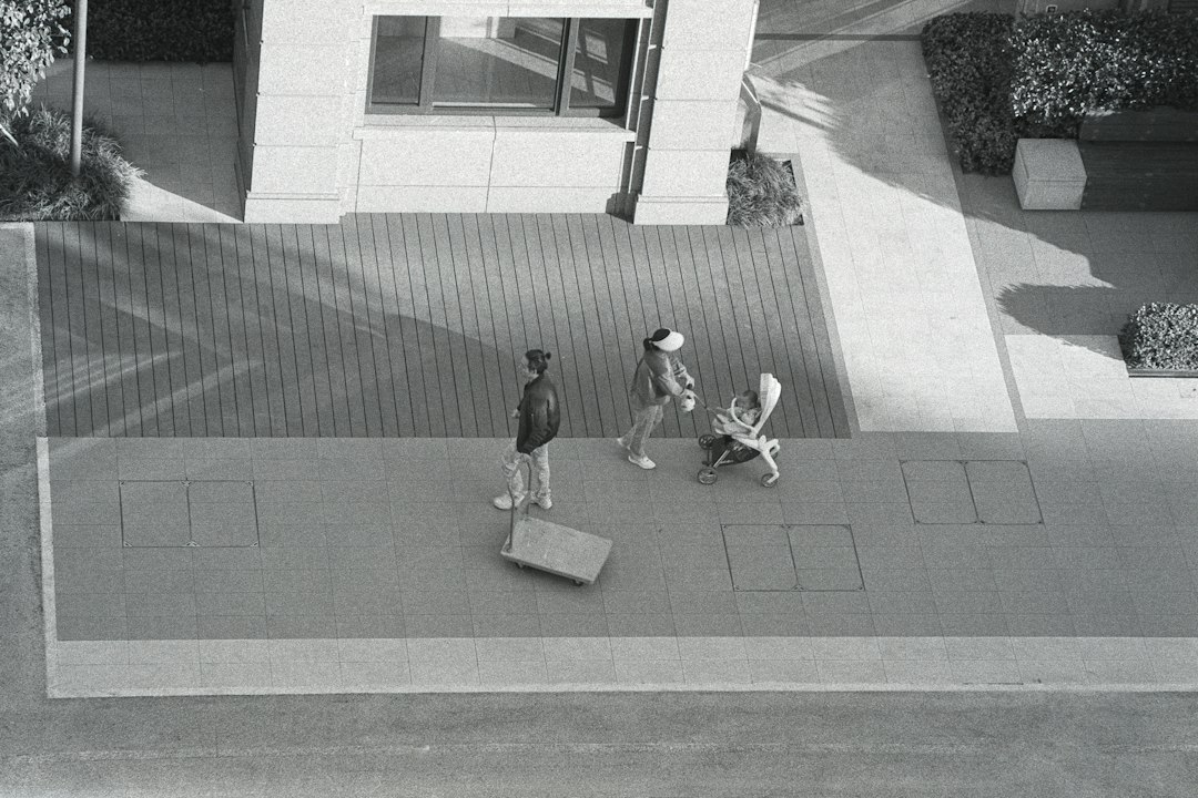 a black and white photo of two people walking down a sidewalk