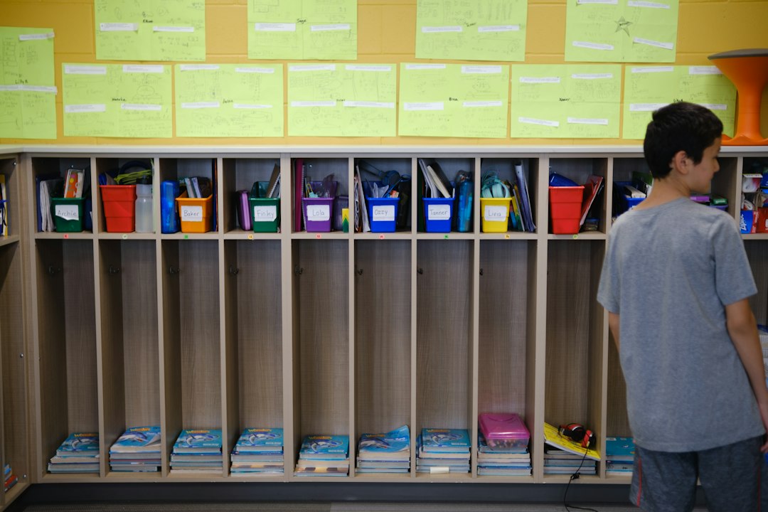 A student in a grey t-shirt facing wooden cubbies with colorful storage bins