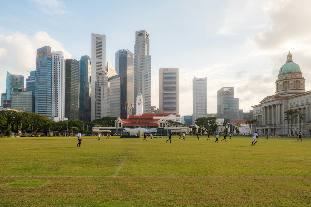 People playing soccer on a green field before the Singapore skyline