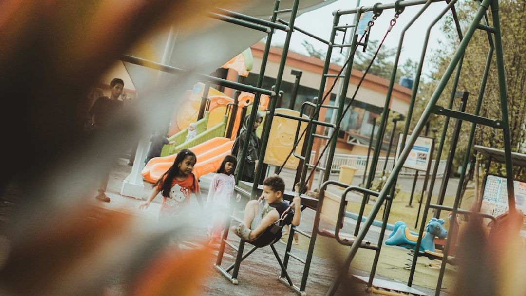 Children are playing at a playground on swings.