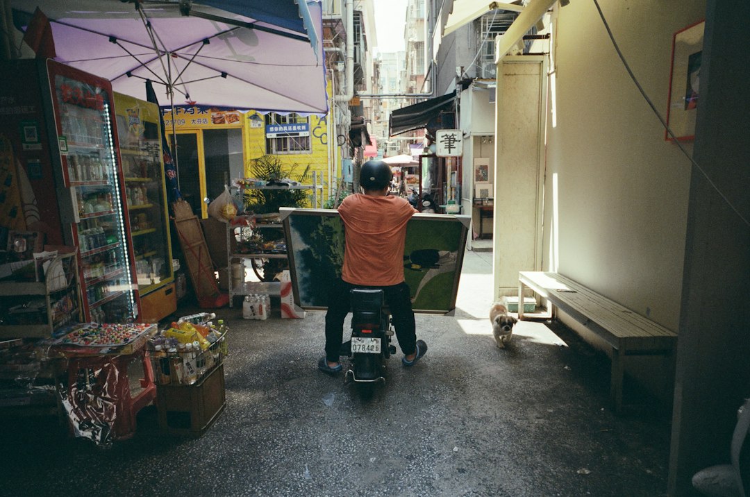 A person on a scooter in a narrow, cluttered alleyway