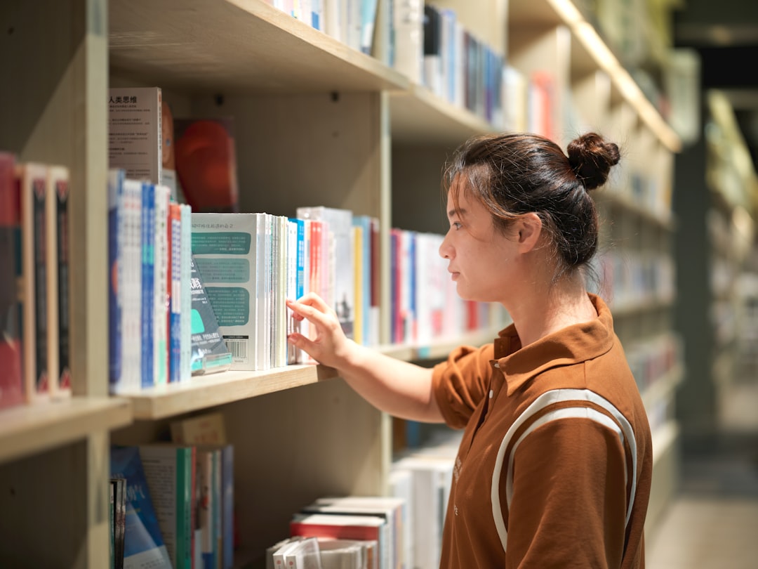 A woman looking at a book on a shelf in a library