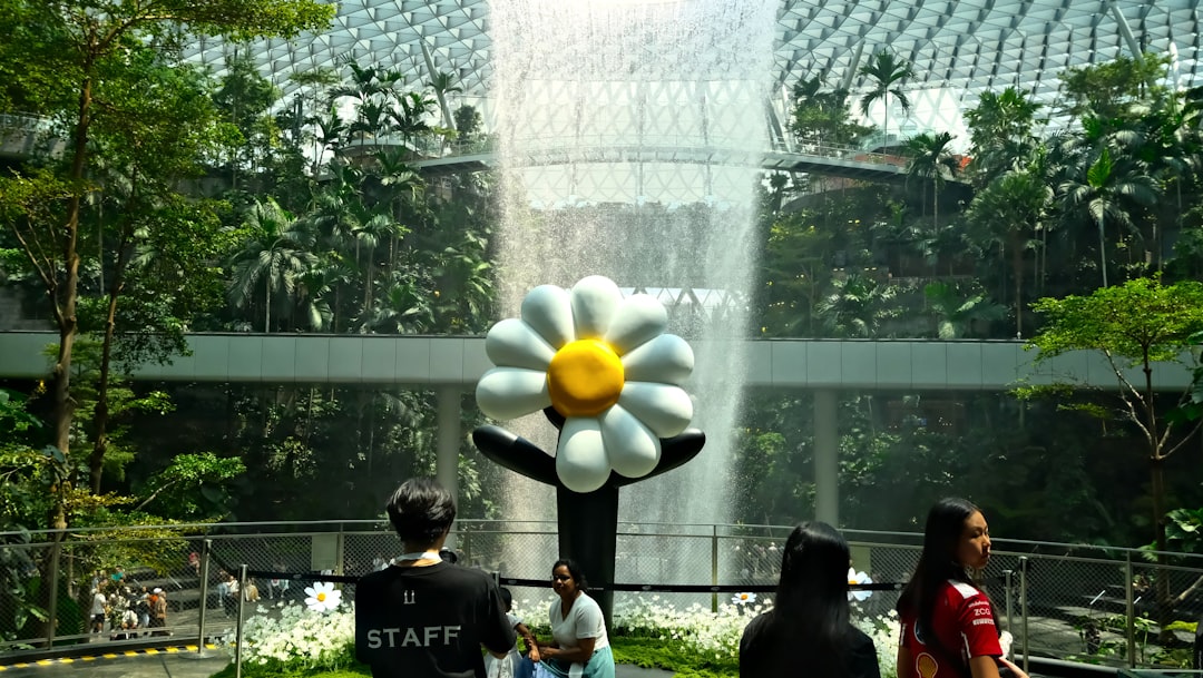 Giant flower sculpture with waterfall in lush indoor garden.