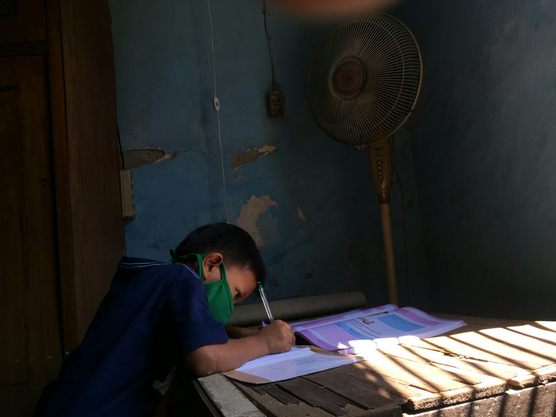 man in blue shirt writing on white paper