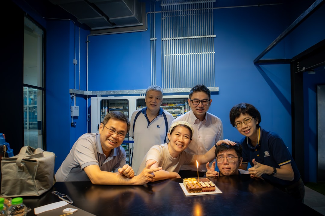 A group of people standing around a table with a cake