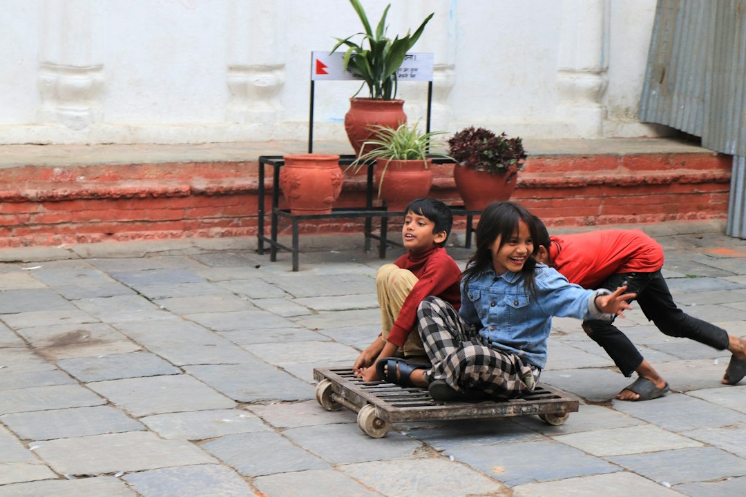 Three children playing with a homemade wooden cart outdoors