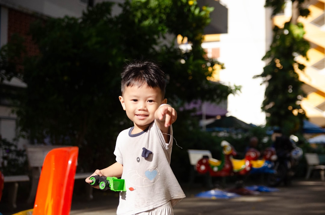 a young boy holding a green toy in his hand