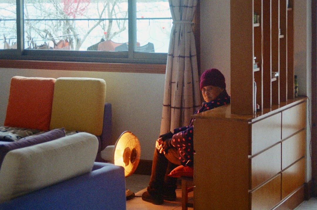 Woman sitting by a heater in a living room.