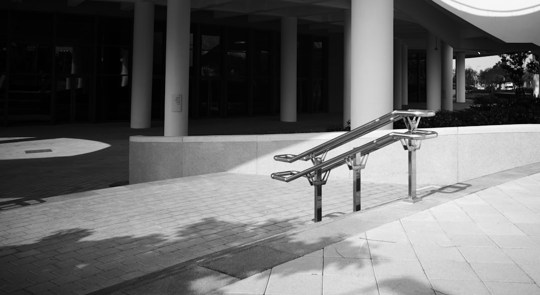 Modern metal bench with shadows on pavement.