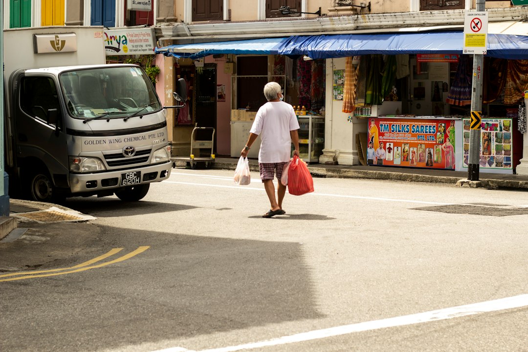 man in white t-shirt and red shorts walking on sidewalk during daytime
