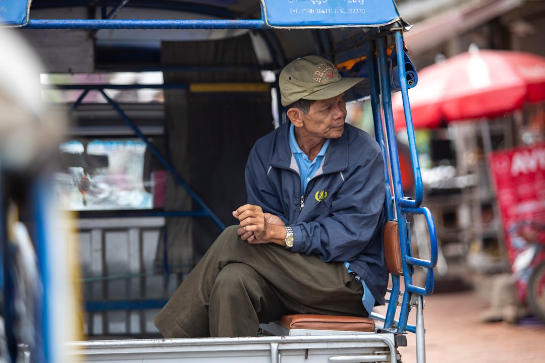 A man in a blue shirt and hat sitting on a cart
