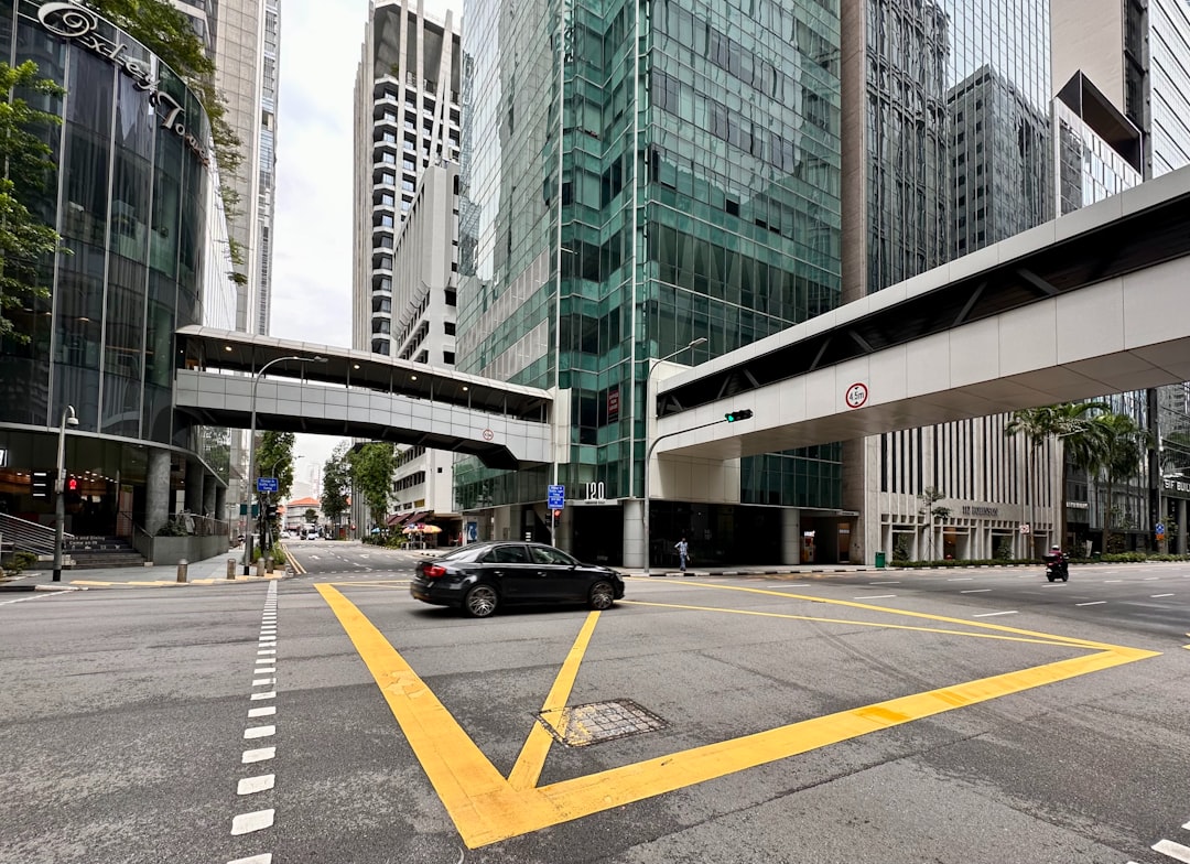 a black car driving down a street next to tall buildings