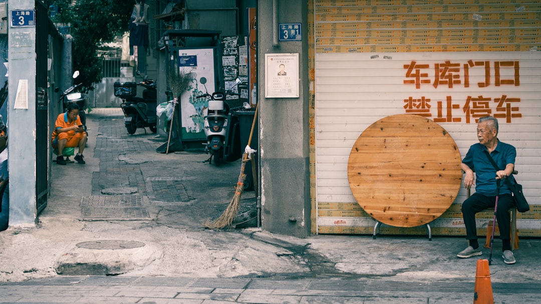 Man sits outside a shop with wooden circle decoration.