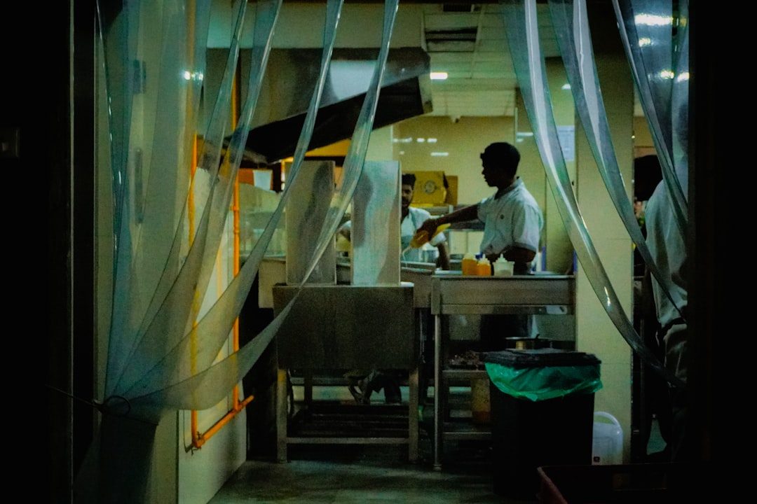 A chef working in a kitchen seen through plastic strips.
