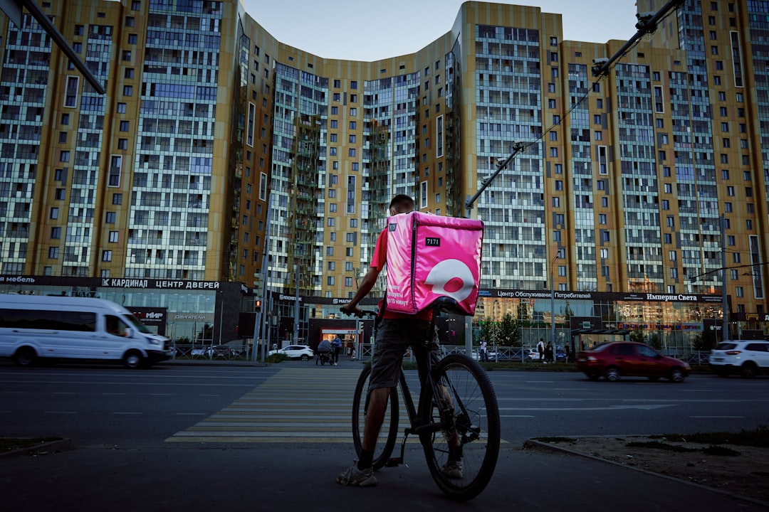 man in red shirt riding bicycle on road during daytime