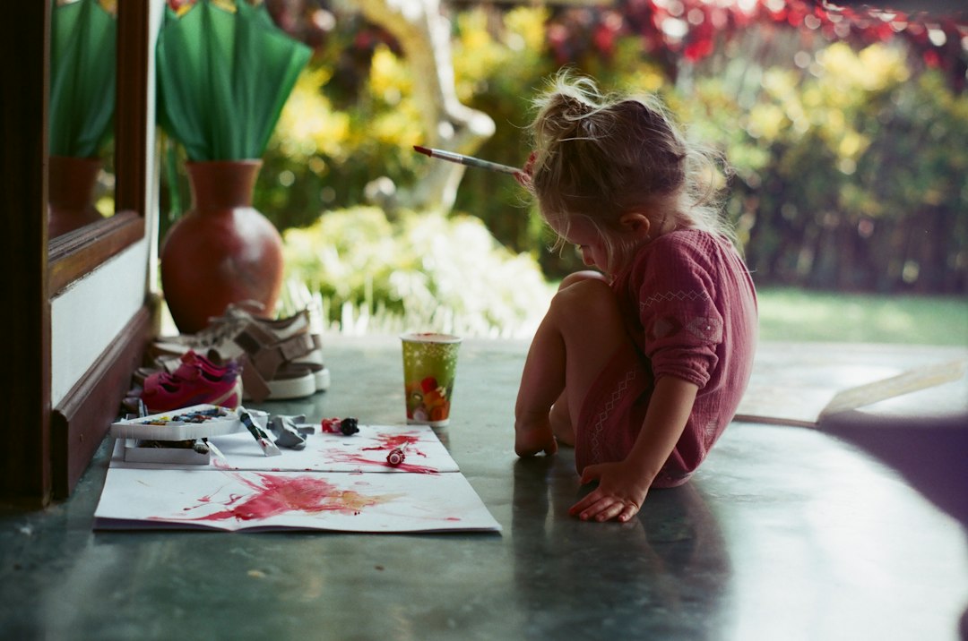 girl in pink shirt sitting on floor while writing