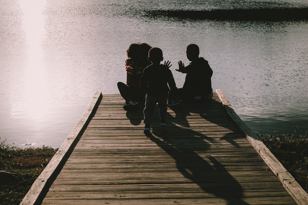 a group of people sitting on a dock next to a body of water