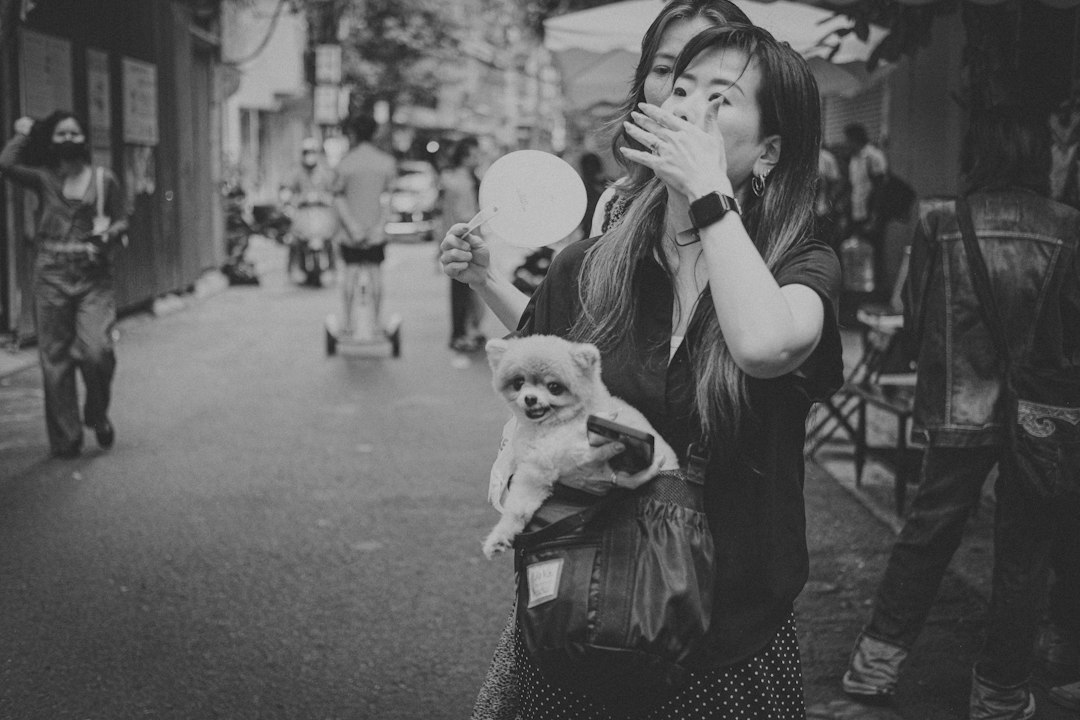 a black and white photo of a woman holding a small dog