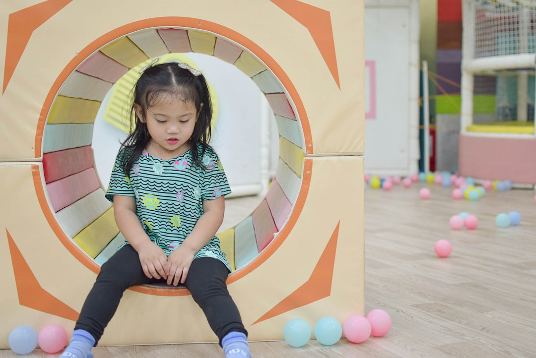a little girl sitting on a chair in front of a wall