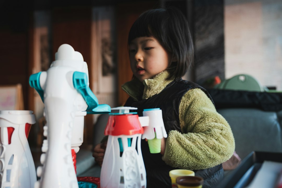 girl in brown sweater holding white and red plastic bottle