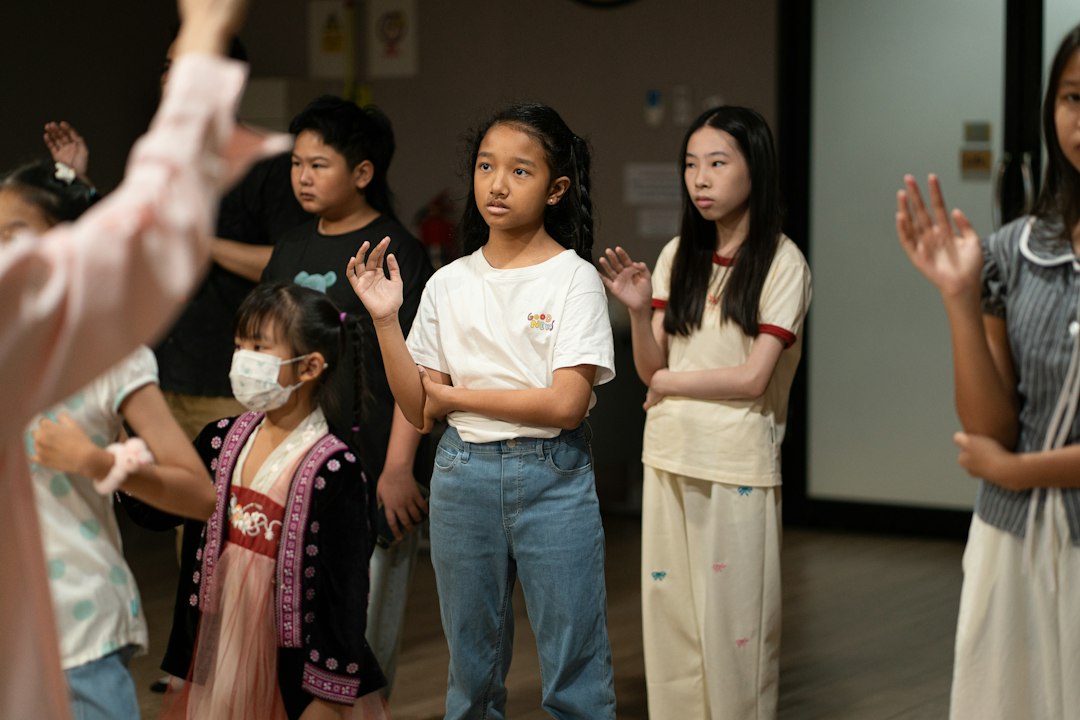 A group of children raising their hands in a classroom setting