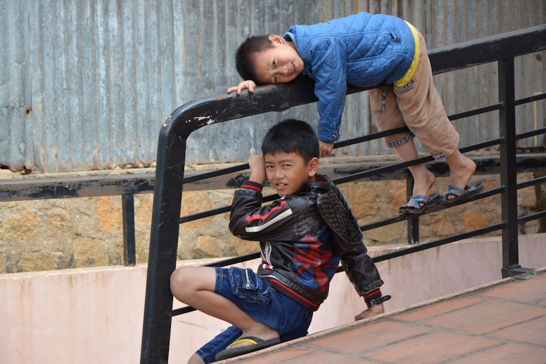 2 boys climbing on black metal ladder during daytime