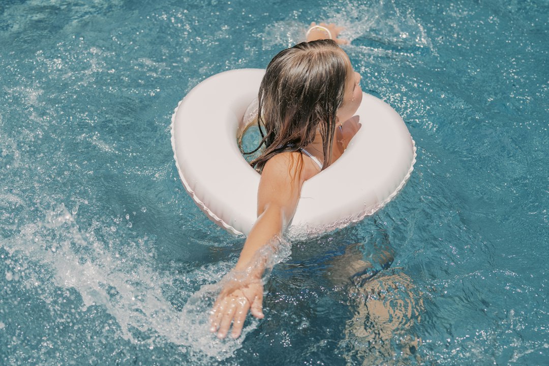 Woman floating in blue swimming pool with white inflatable ring