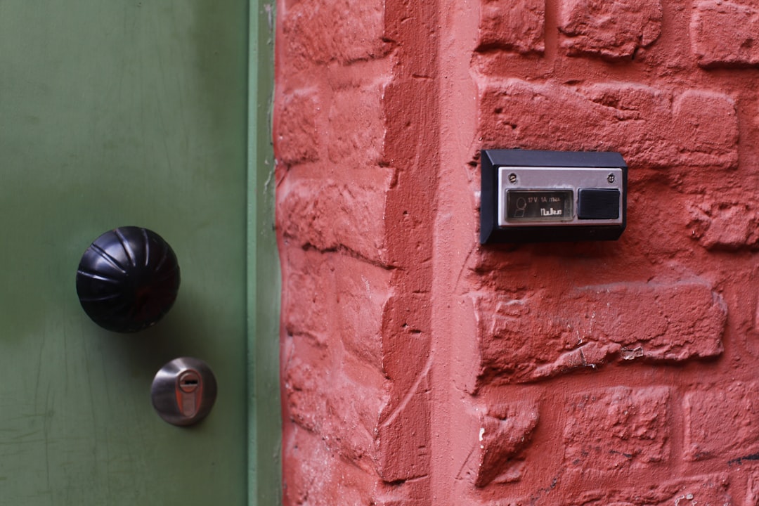 a door handle on a green door with a red brick wall
