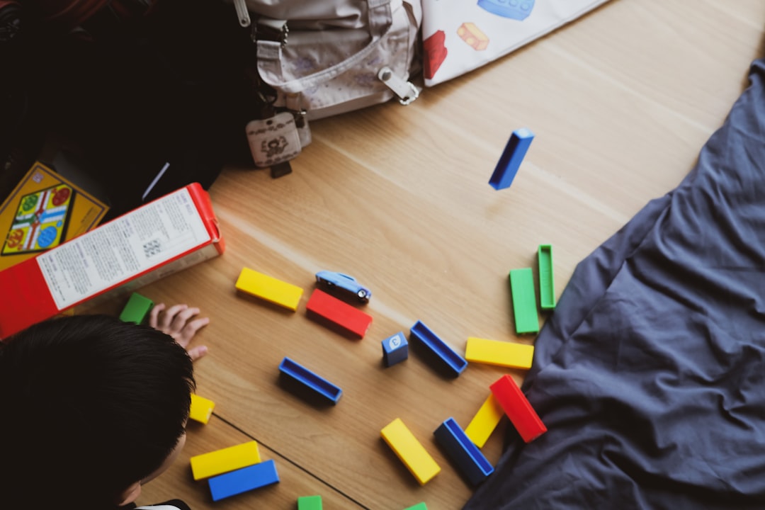 Child playing with colorful building blocks on wooden floor.