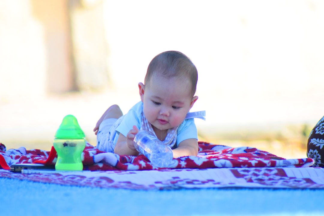 A baby laying on a blanket on the ground