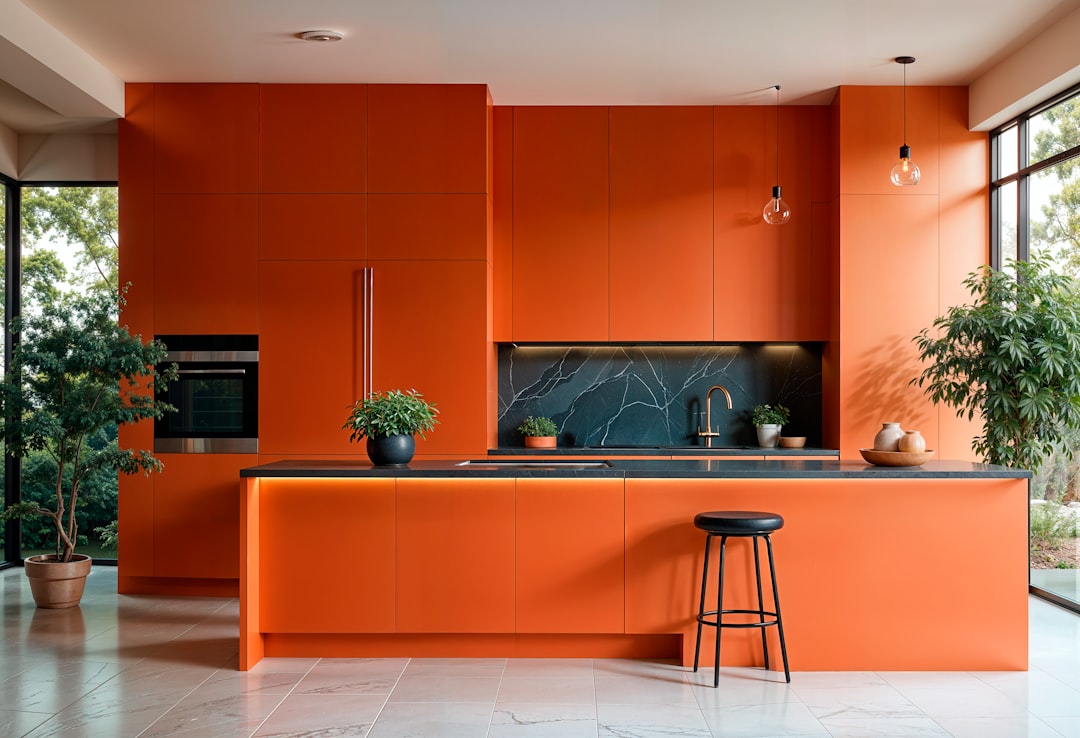 Modern orange kitchen with island and large windows.