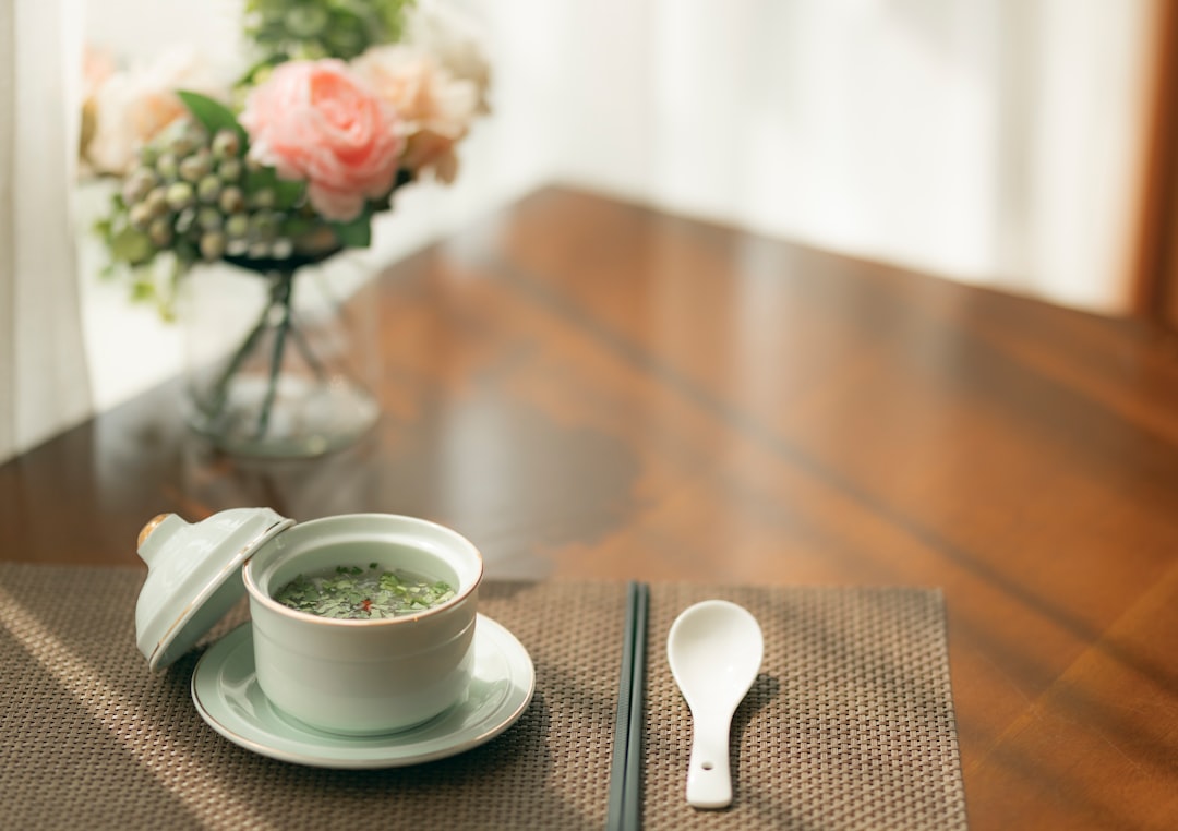 white ceramic teacup on white ceramic saucer beside silver spoon
